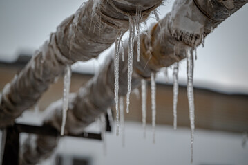 Pipes in poor countries in winter. Icicles on an old pipes in winter.  - obrazy, fototapety, plakaty