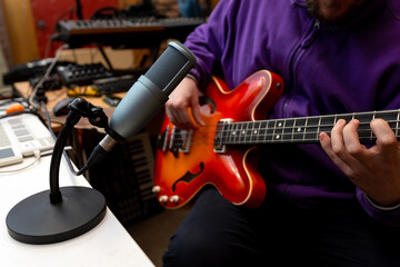 Obraz na płótnie Canvas Man records bass guitar sound on professional microphone in recording studio