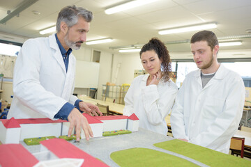 students with teacher looking at architectural model