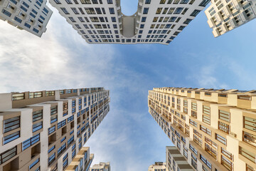view up from ground to blue sky among skyscrapers, look at house from bottom up - obrazy, fototapety, plakaty