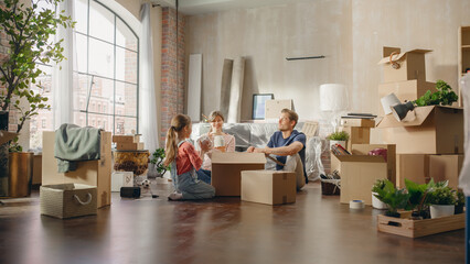 Happy Homeowners Moving In: Lovely Couple Sitting on the Floor of Cozy Apartment Unpacking...