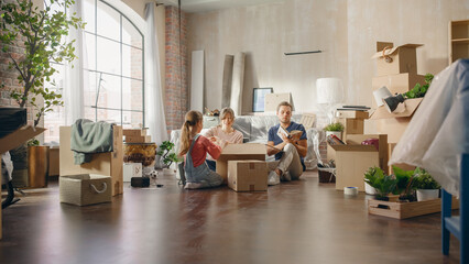 Fototapeta na wymiar Happy Homeowners Moving In: Lovely Couple Sitting on the Floor of Cozy Apartment Unpacking Cardboard Boxes, Little Daughter Joins them. Cheerful Day, Happiness, Sweet Home for Young Family Having Fun