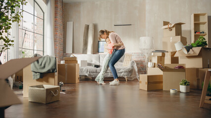 Truly Happy Mother and Daughter Moving Into their New Cozy Home. Cheerful Young Family, Girls Have Fun, Dance, Hug in the Middle of Apartment. Living Room Has Unpacked Cardboard Boxes.