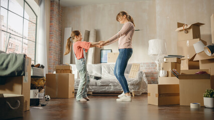 Fototapeta na wymiar Truly Happy Mother and Daughter Moving Into their New Cozy Home. Cheerful Young Family, Girls Have Fun, Dance, Hug in the Middle of Apartment. Living Room Has Unpacked Cardboard Boxes.