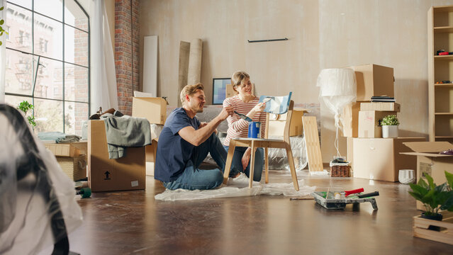 Family Moving in and Home Renovations: Couple in Love Painting Furniture Chair for Cozy Home. Boyfriend and Girlfriend Make Apartment Comfortable with Art, Color. Smiles and Happiness.