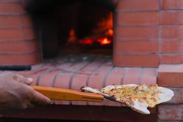 Cooking pizza in ove. ?ook takes cooked focaccia out of oven using shovel