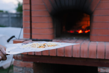 Cooking focaccia in uve. Chef holds focaccia on large shovel before cooking in professional oven