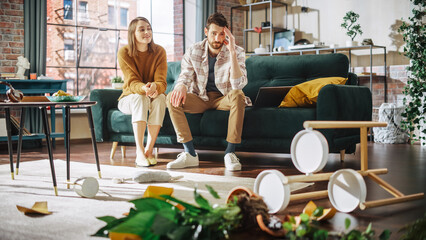 Funny Moment: Ruined Potted Flower by Dog After Overturning it and Making Mess in the Whole Apartment. Couple Sitting on Couch with look of Disbelief, Frustration. Woman Smiling - obrazy, fototapety, plakaty