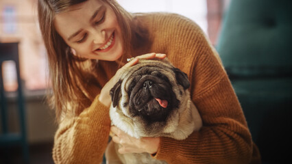 Close-up Portrait Beautiful Woman Holding Adorable Little Pug at Home. Girl Plays with Her Dog, Gorgeous Pedegree Best Friend. She Pets and Scratches Super Happy Doggy, Have Fun in the Living Room