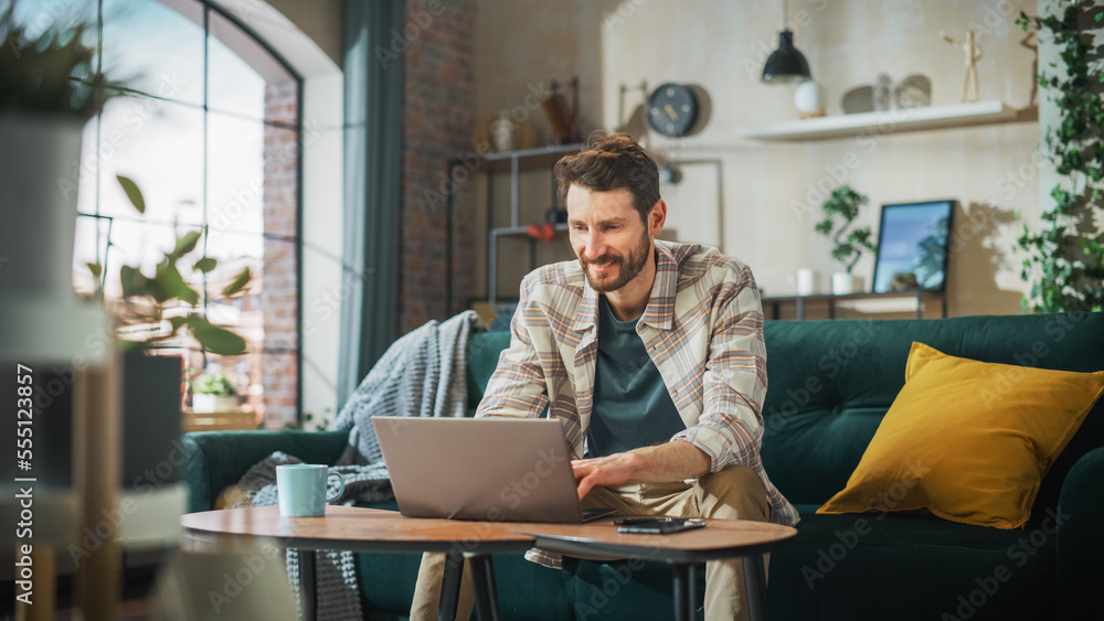 Poster portrait of smiling middle aged man working from home on a laptop computer in sunny cozy apartment. 