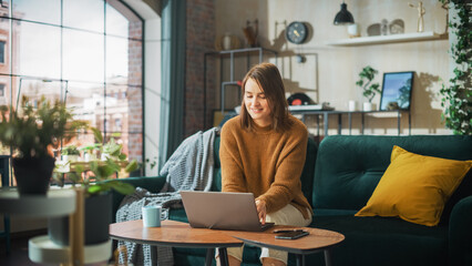 Portrait of Smiling Young Woman Working from Home on Laptop Computer in Sunny Cozy Apartment....