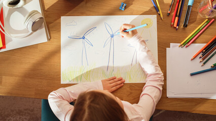 Top View: Little Girl Drawing Beautiful Wind Turbines that Look Like Flowers. On Sunny Day Smart...