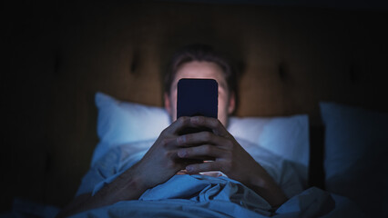 Anonymous Man Uses Smartphone in Bed at Home at Night. Handsome Guy Browsing Social Media, Reading...