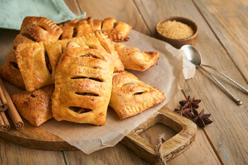 Hand pies. Mini puff pastry or hand pies stuffed with apple and sprinkle sugar powder in wooden plate. Homemade pie snack with crust for breakfast rustic photo.  Copy space.