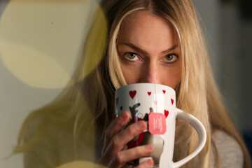 schöne blonde Frau mit Tasse in der Hand, direkter Blick, Portrait Gesicht 