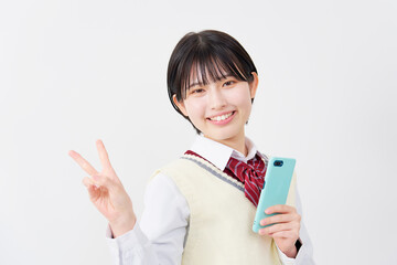 スマホを持ってピースサインする女子高生　白背景