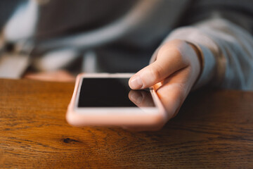 A young girl in a cafe uses the phone. People use technology. Cafe city lifestyle. Colorful portrait of happy pretty girl.