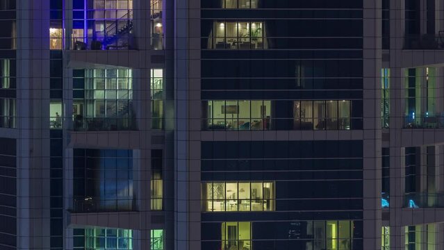 Windows in high-rise building exterior in the late evening with glowing and blinking interior lights on timelapse. Aerial top view