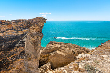 A small boat seen from cliffs of Taqah Beach along the Arabian Sea at Salalah, Oman.