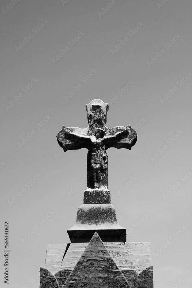 Wall mural a statue of jesus christ on the cross standing against the sky in black and white.