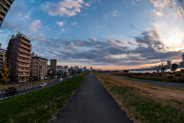 View of a path with buildings on the left and the riverside on the right during a sunny day
