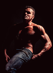 Fototapeta na wymiar Sport workout bodybuilding concept. Handsome big muscles man posing at studio. Leather belt, jeans