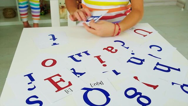 English cards are taught by children at the table. Selective focus.