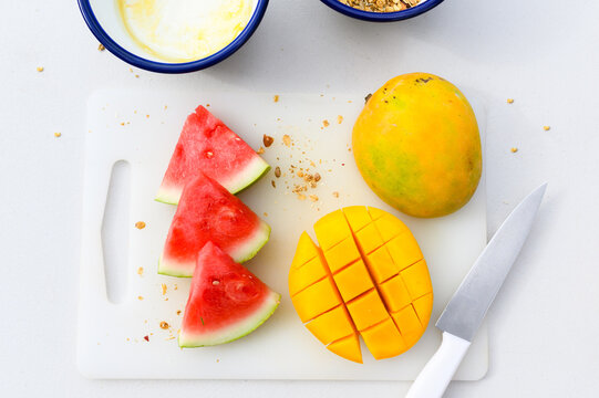 Slices of watermelon and chopped mango on cutting board