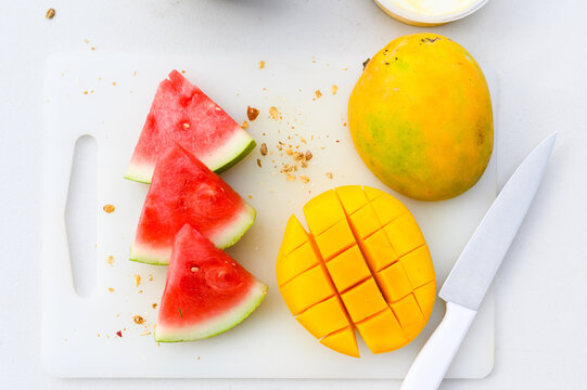 Slices of watermelon and chopped mango on cutting board