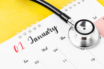 The January 2023 deskcalendar and medical stethoscope medical on yellow background, schedule to check up healthy concepts.