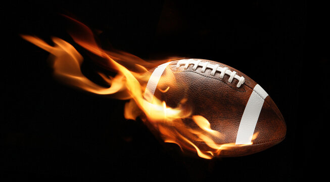 American football ball with bright flame flying on black background.