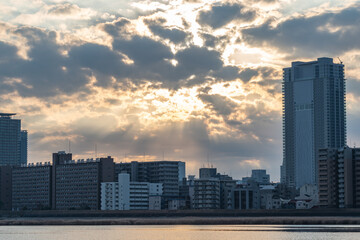 View of a river and some buildings covering by the sunlight during a cloudy day