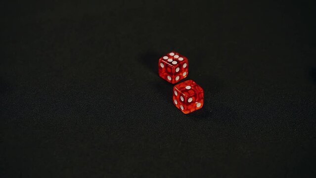 Two red dice roll six and one for total of seven points on black background, Craps, Slow motion