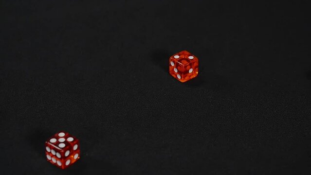 Red casino dice being rolled and settling on seven on black background, Craps, Slow motion