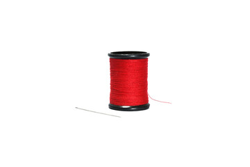 Red sewing thread in black reel with sewing needle isolated on white background.