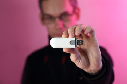 gsm modem in the fingers of a person's hand in a black sweatshirt