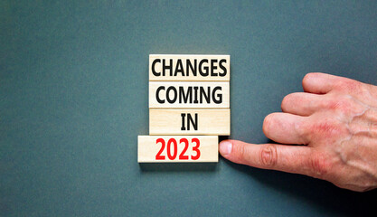 Changes coming in 2023 symbol. Concept word Changes coming in 2023 on wooden blocks. Businessman hand. Beautiful grey table grey background. Business and changes coming in 2023 concept. Copy space.