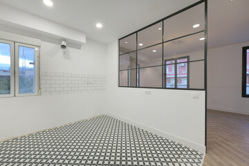 Empty kitchen with hydraulic tiles with a geometric pattern with a glass and black metal partition...
