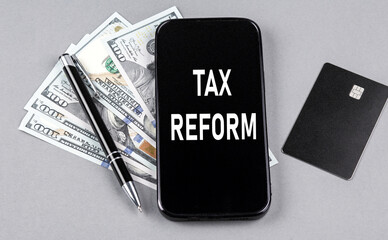 Credit card and text TAX REFORM on smartphone with dollars and pen. Business concept