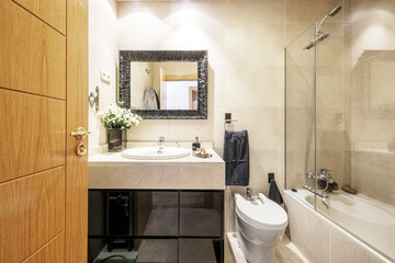 Toilet with light colored marble tiles, veined marble cabinet and black gloss wood base, framed...