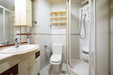 Bathroom with small white porcelain sink with old shower cabin with massage jets and music