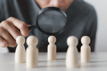 Hand Holding A Magnifying Glass Focusing On Wooden Figure .job search, human resources, hiring...