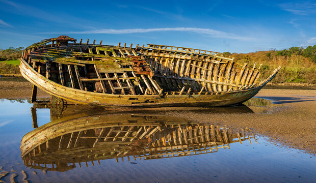 Old wrecked fishing boat reflected in a tidal pool