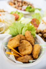 Nuggets in white paper cup with vegetables and other food