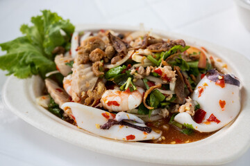 Spicy salad with seafood and vegetables decorated in a white plate