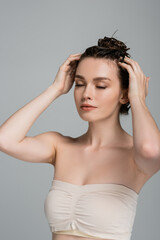 Fototapeta premium pretty young woman with closed eyes washing hair isolated on grey
