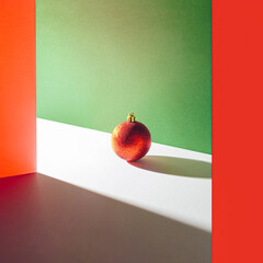 Cool artsy composition with shiny red glitter holiday ornament on geometric colorful background. Minimal Christmas concept.