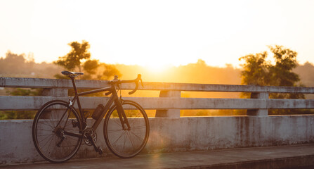 Road bike parked on a beautiful road sunset, on the bridge warm light with copy space.