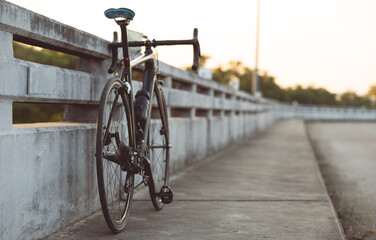 Fototapeta na wymiar Road bike parked on a beautiful road sunset, on the bridge warm light with copy space.