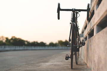 Road bike parked on a beautiful road sunset, on the bridge warm light with copy space.